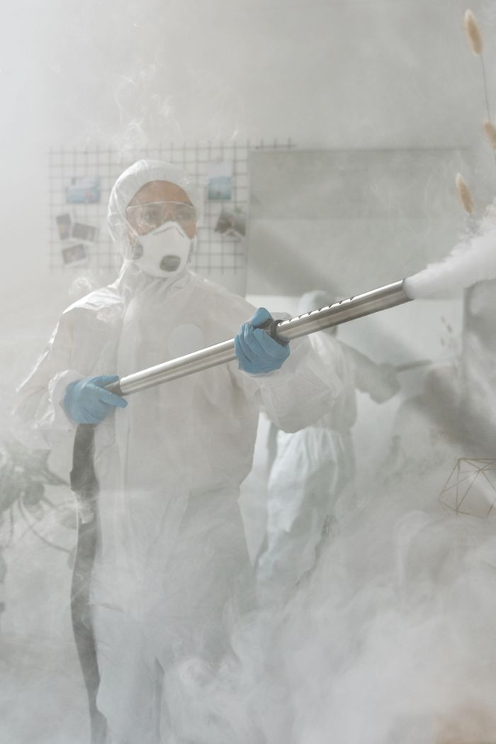 creative-03 A worker in full protective equipment is fumigating a room to help ensure it is sterilized against viruses.